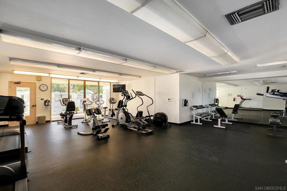 Interior view of a gym area with exercise equipment and mirrors.