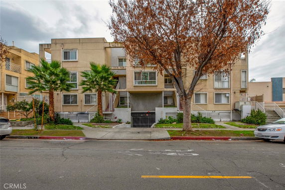 Front view of a multi-story apartment building with a gated entrance.