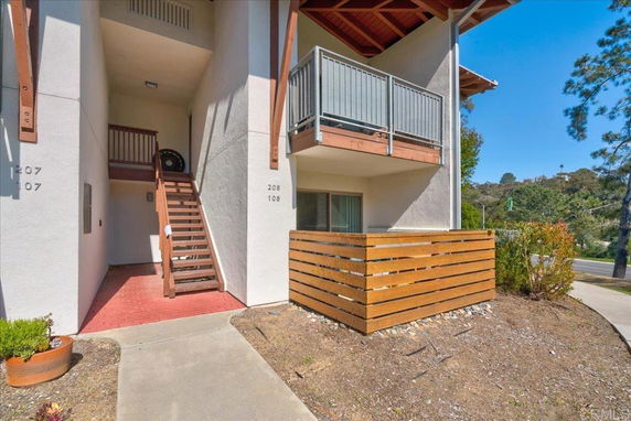Front view of a two-story building with wooden balcony and external staircase entrance.