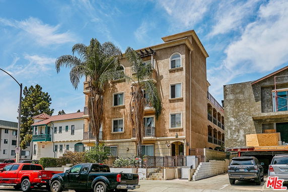 Front view of a multi-story apartment building with palm trees.