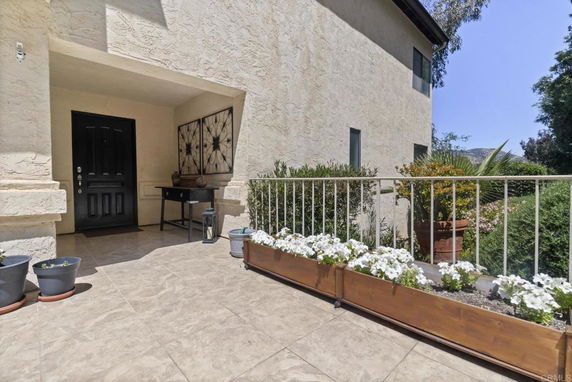 Front entrance of a house with a covered porch and decorative planters.