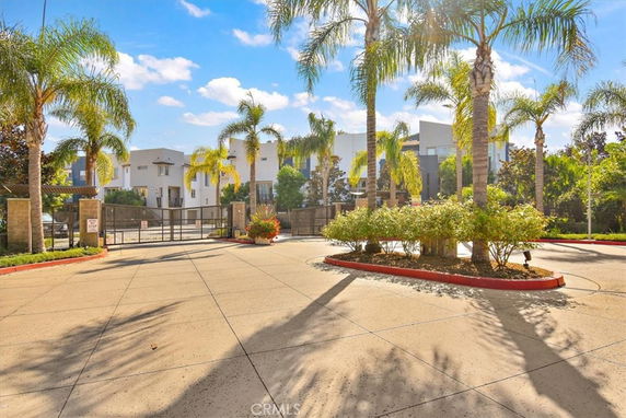 Front view of a modern building with gated entrance and palm trees.