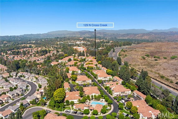 Aerial panoramic view of a residential area with multiple houses and a central swimming pool.
