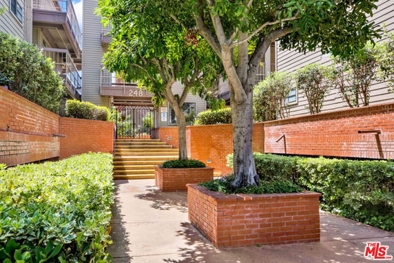Entrance of a multi-story residential building with a brick facade and gated entry.