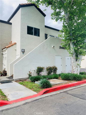 Front view of a two-story building with external staircase and flat roof.