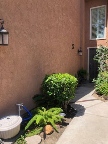 Side view of a house with textured walls and a window above a pathway.