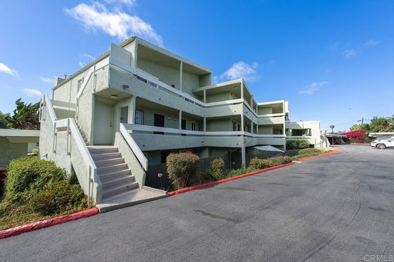 Front view of a multi-story building with a staircase leading to the entrance.