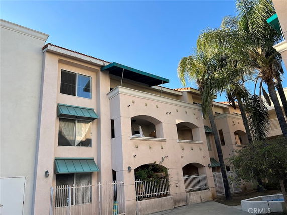 Front view of a multi-story residential building with balconies and green awnings.