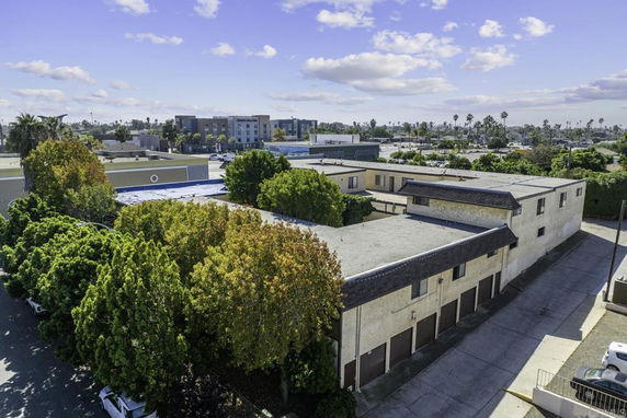 Front view of a multi-story building surrounded by trees, with a paved driveway.