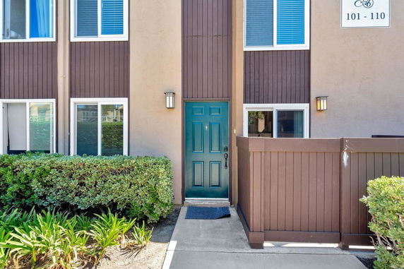Front view of a two-story building with a green door and brown siding.