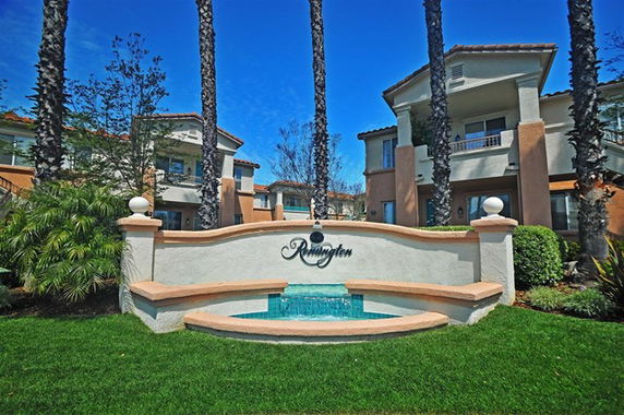 Front view of a multi-story building with decorative wall and fountain.