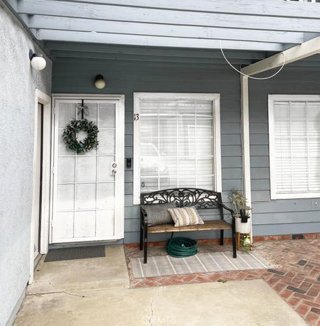 Front view of a house entrance with a seating area and decorative door wreath.