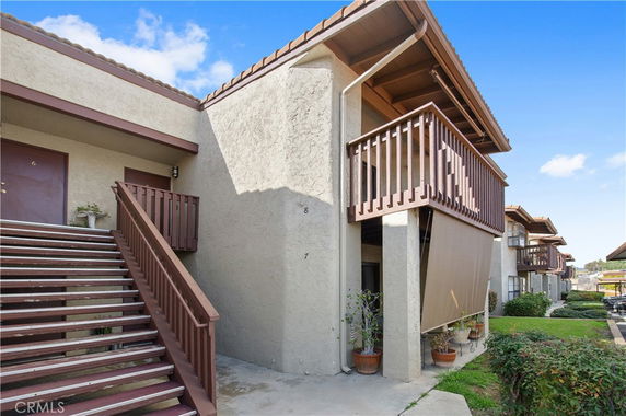 Front view of a residential building with external staircase and balconies.