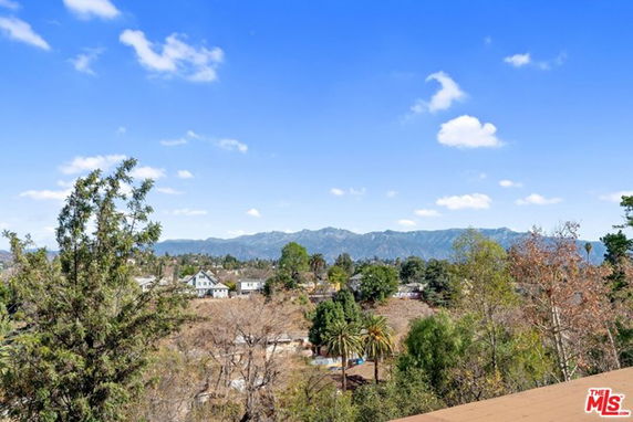 Panoramic view of a hilly area with scattered houses and trees under a clear sky.