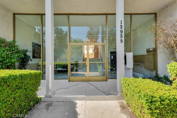 Front view of a modern building with large glass windows and entrance door.