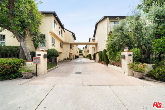 Front view of a residential building with a paved driveway and greenery on either side.