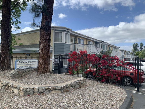 Front view of a two-story condominium complex with a gated entrance and parking area.