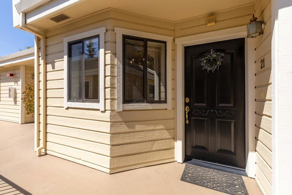 Front view of a beige building with a dark brown door and two windows.