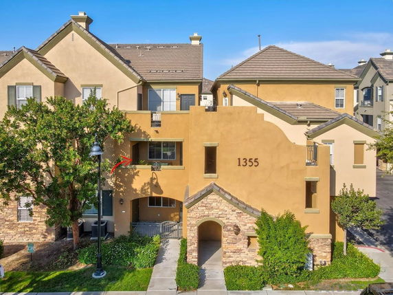 Front view of a multi-story house with beige stucco exterior and stone accents.