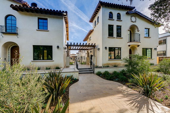 Front view of a Mediterranean-style house with arched windows and a central walkway.