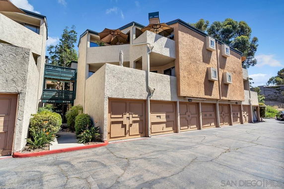 Front view of a multi-story residential building with garages on the ground floor.