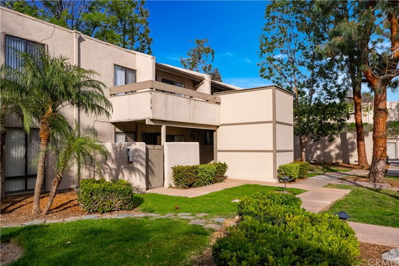 Front view of a two-story house with a balcony and beige exterior walls.