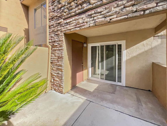 Front view of a structure with a sliding glass door and stone wall accents.