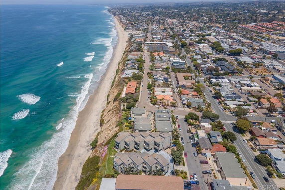 Aerial view of a coastal city with residential and commercial buildings along a beach.