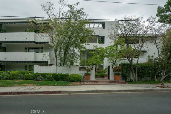 Front view of a multi-story building with balconies and greenery.