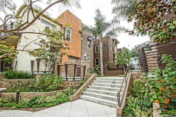 Front view of a multi-story residential building with stairs leading to the entrance.