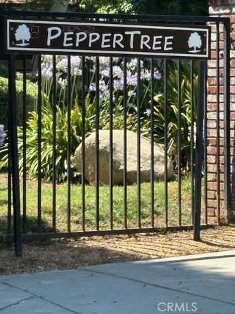 Metal gate with 'PepperTree' sign and greenery behind.