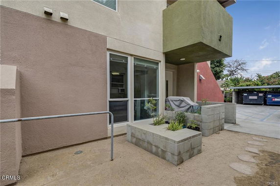 Exterior view of a modern building with large windows and a small patio area.