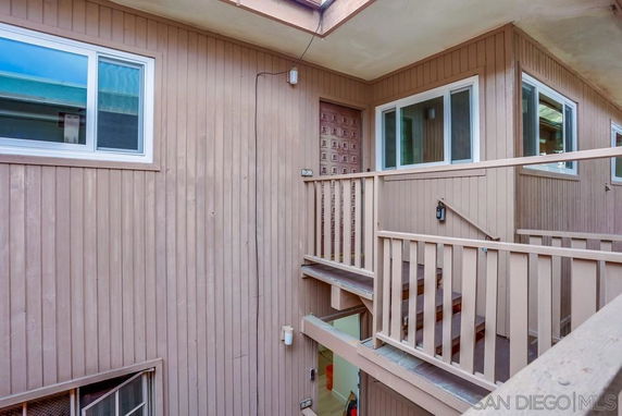 Exterior staircase and entryway of a multi-level building with wooden siding.