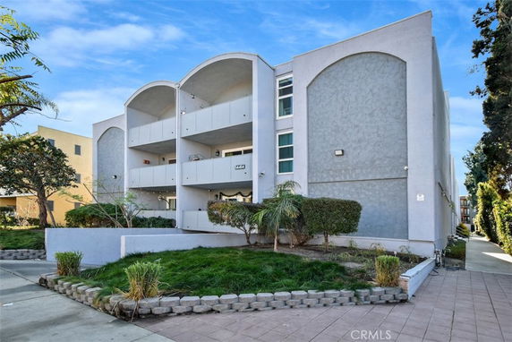 Front view of a multi-story residential building with an arched balcony design.