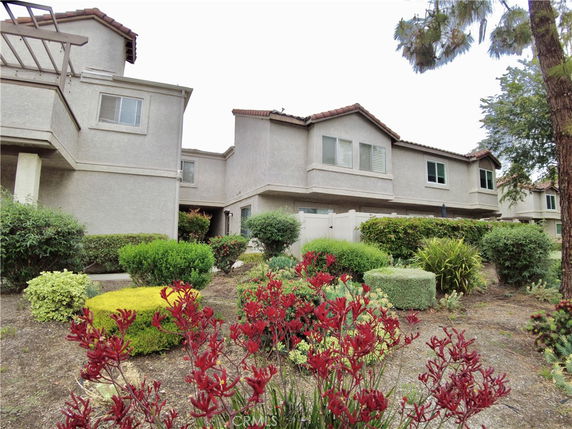 Front view of a two-story residential building with beige exterior and red tile roof.