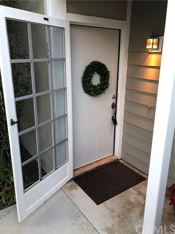 Entryway of a house with a wreath on the front door and a porch light.