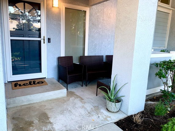 Front view of a house entrance with a small porch and seating area.