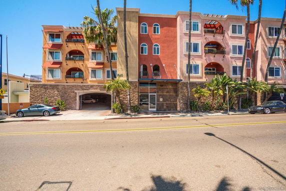 Front view of a multi-story residential building with balconies and an arched entrance.