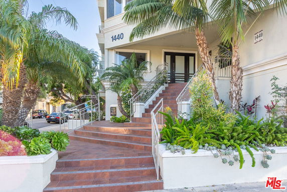 Front view of a multi-story building with grand entry steps and lush landscaping.