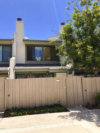 Front view of a two-story townhouse with a fence and chimney.