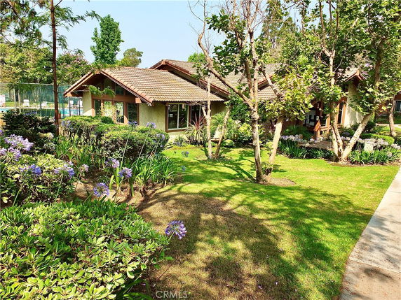 Front view of a single-story house with a tiled roof and large windows, surrounded by greenery.