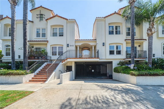 Front view of a multi-story townhouse with a gated entrance and stairways.