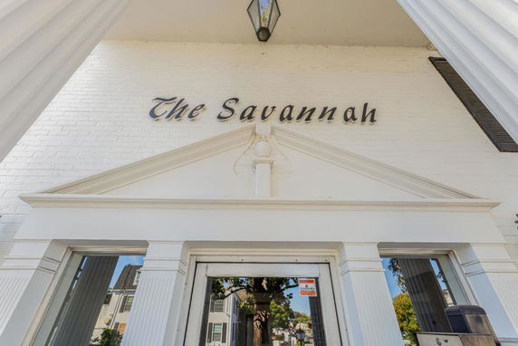 Entrance view of a building with white brick exterior and a sign that reads 'The Savannah'.