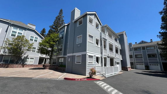 Front view of a multi-story building with balconies and parking spaces.