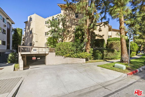 Front view of a multi-story residential building with trees in front.