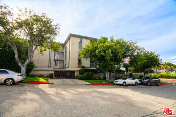 Front view of a multi-story apartment building with parking area in front.