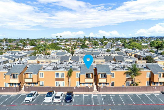 Distant view of a residential neighborhood with multiple buildings and parking spaces in front.