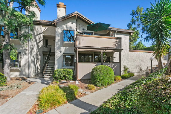 Front view of a two-story house with a balcony and outdoor staircase.