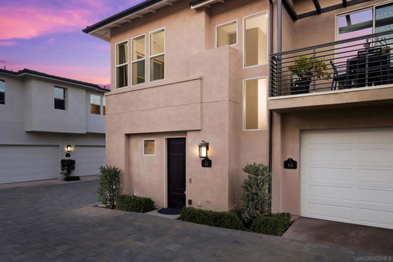 Front view of a modern multi-story house with a garage and balcony.