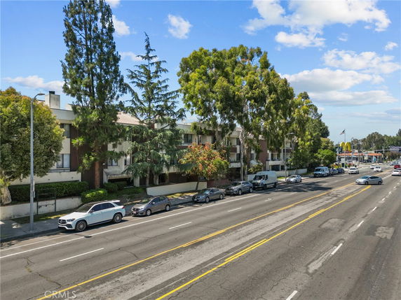 Front view of a multi-story residential building along a street with parked cars.